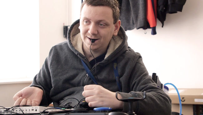 Paul_1000_osd Seated man in hoodie using adpated gaming setup