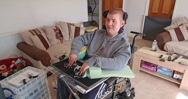 Young man in wheelchair using adapted gaming controller setup