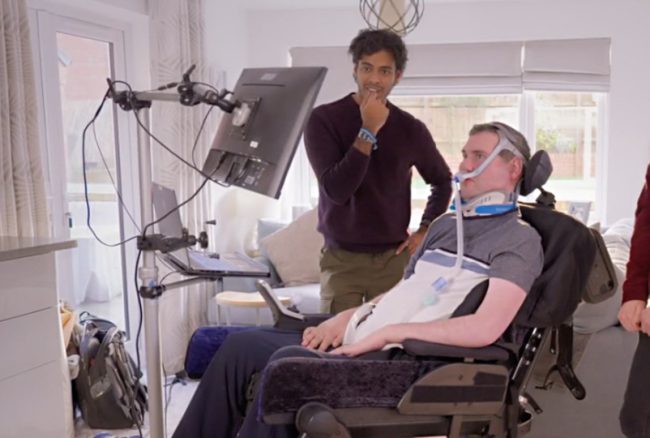 sam_800 Ventilated man in a wheelchair looking at a screen, another man watches.