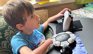 Young girl using two assistive gaming controllers